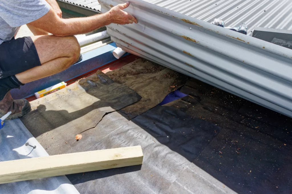Builder looking under a commercial flat roof for a water leak.